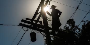 A power worker works on a pole.