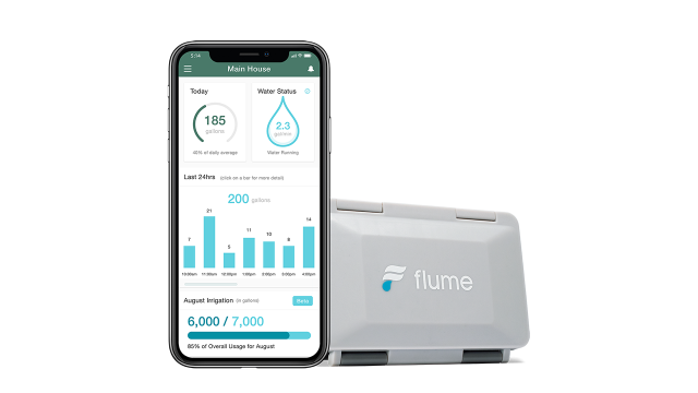A Flume smart home water monitor device is positioned to the right of a smartphone showing the Flume app’s dashboard.