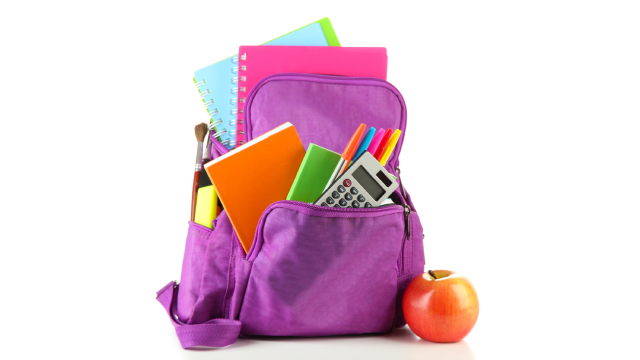 A purple backpack with a red apple sitting next to it. The backpack is filled with school supplies like notebooks, colored pens, highlighter pens, and a calculator.