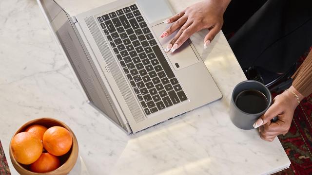 person on laptop and holding mug