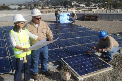 LADWP Crew members working on installing solar panels on flat rooftop of building.