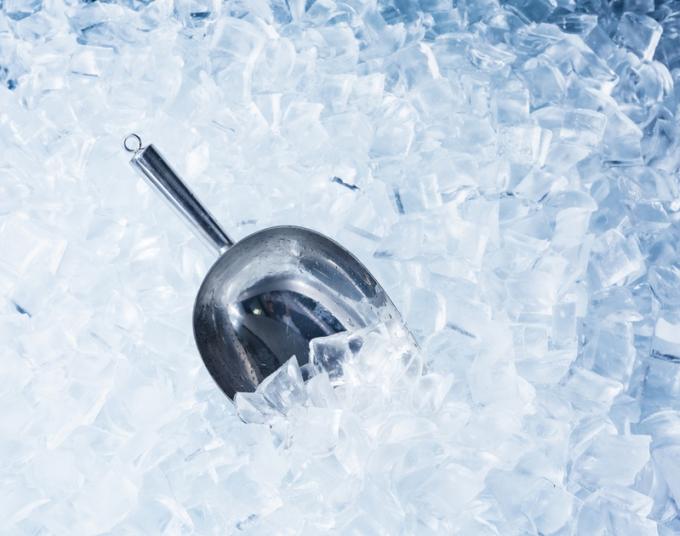 A metal scoop rests in a pile of ice.