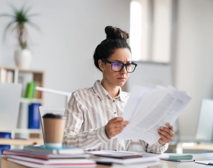 Woman looking and holding several papers in her hand.