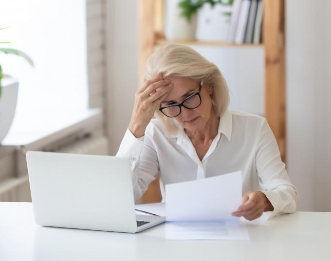 woman in front of laptop and holding paper