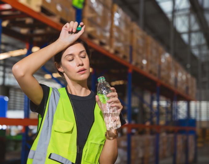 Woman working in hot environment drinking a bottle of water.