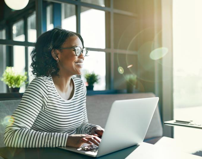 woman sitting in front of laptop with sun shining on her