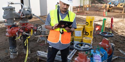 employee at job site with dirt and water valves in background