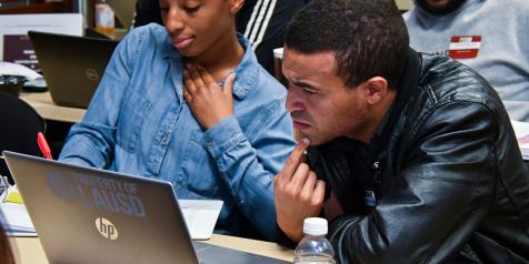 woman writing and man staring at laptop