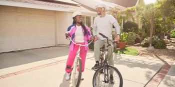 A man and a woman sitting on bicycles in a driveway