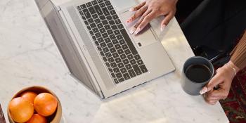 person on laptop and holding mug